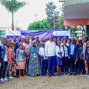 This image shows a large group of people, including both men and women, gathered outside a building at the EAUR Nyagatare campus. In the center, a few individuals are standing with a visually impaired person using a white cane, symbolizing the focus on disability inclusion. The group consists of students, faculty, and community members, standing in front of a banner for the ANSWER Project, which promotes understanding of disability and inclusion in higher education institutions. 